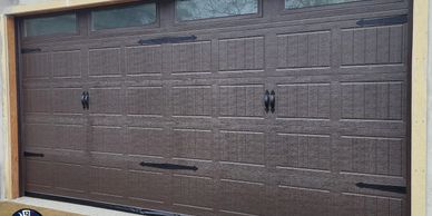 A closed brown garage door with decorative handles and hinges.