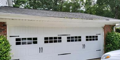 White garage door with small windows and black decorative handles and hinges.