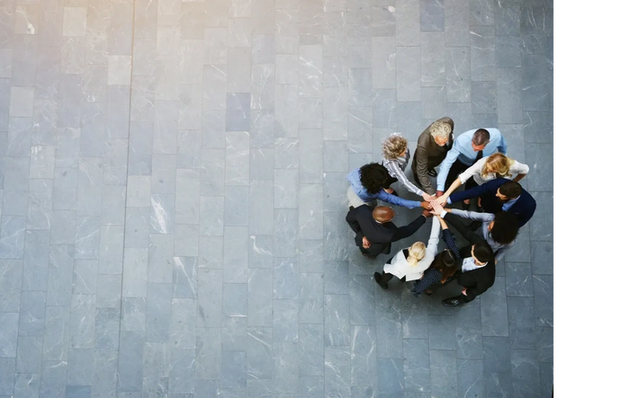 Business team joining hands in a circle, symbolizing unity and teamwork.