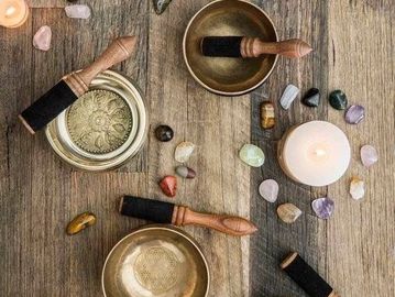 Singing bowls, incense sticks, and crystals arranged on a wooden surface.