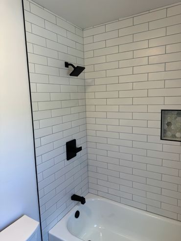 Modern bathroom with white subway tiles and matte black fixtures.