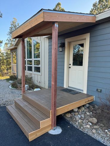 New wooden porch with steps and a small roof at a house entrance.