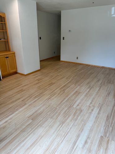 Empty room with light wood flooring and white walls.