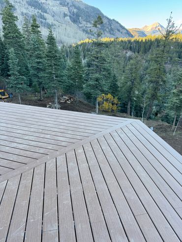 Wooden deck overlooking a forest and mountain landscape at sunrise.