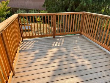 Wooden deck with railing overlooking a garden area.