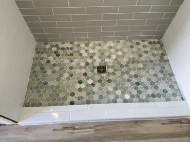 Shower floor with hexagonal mosaic tiles and a square drain.