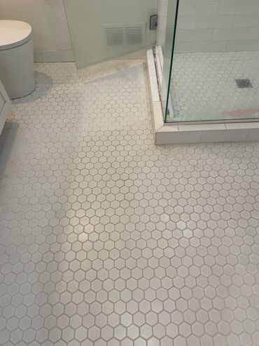 Bathroom floor with hexagonal tiles and a glass shower enclosure.