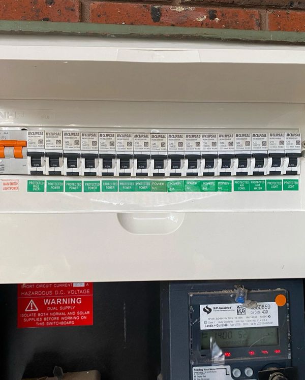 Electrical circuit breaker panel with labeled switches and a warning sign.