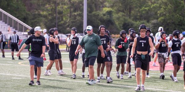 High school football players and coaches on the field during practice or warm-up.