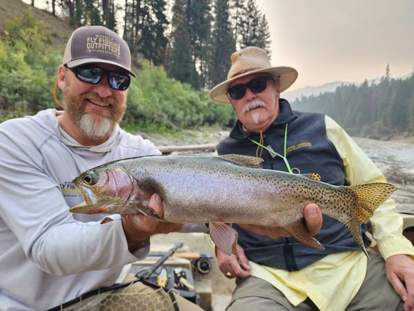 Clark Fork River Montana Fly Fishing guide holding rainbow trout in drift boat with a client