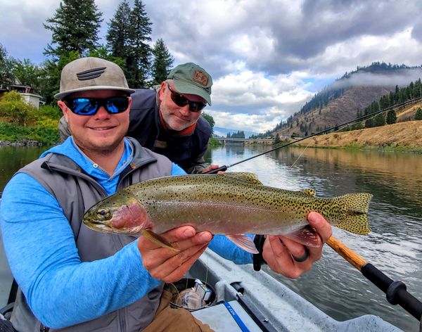 Clark Fork River Rainbow Trout Fly Fishing guide holding a big trout with smiling client behind