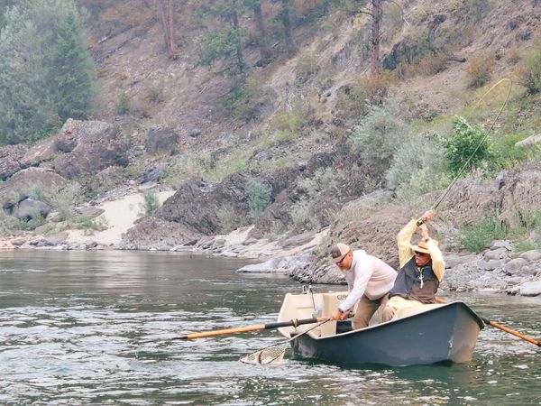 Clark Fork River Fly Fishing Guide landing a fish with the front client leaning back with a bent rod