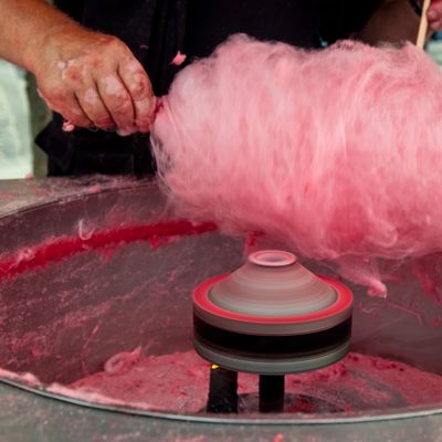 Hand making pink cotton candy with a spinning machine.