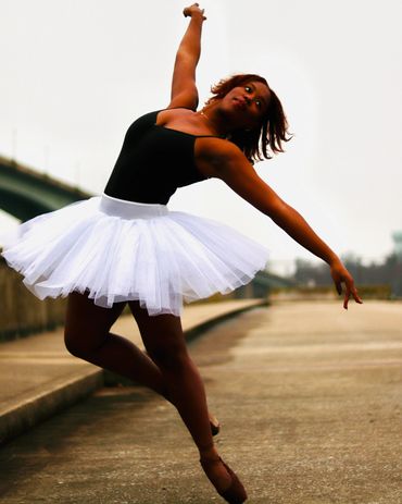 Dancer posing in a white tutu and black leotard, caught as she's falling out of a pose