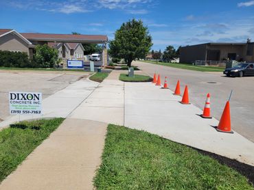 Newly poured concrete driveway marked with orange cones and Dixon Concrete sign.
