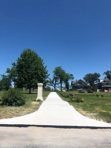 Long concrete driveway leading to houses on a sunny day.