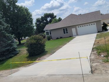 Newly poured concrete driveway with caution tape in front of a suburban house.