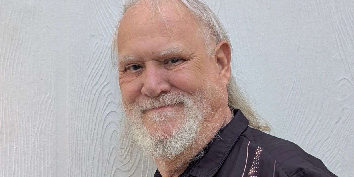 Elderly man with white beard smiling.
