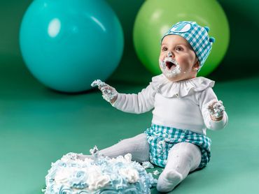 niño 1 año en estudio sentado con tarta