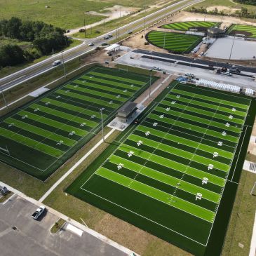 Aerial view of multiple football fields with bright green artificial turf.