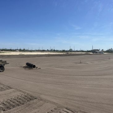 A large, flat construction site under a clear blue sky.