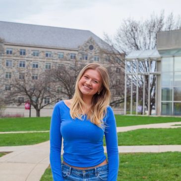 Smiling young woman in blue top outdoors.