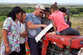 European tourist visiting rural Mongoalia. He is asking for directions by showing a map to a family