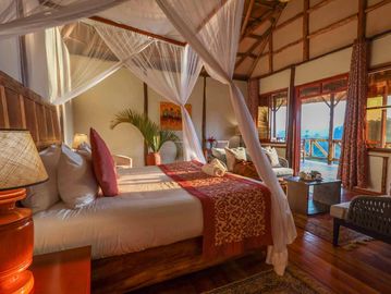 Cozy wooden bedroom with two beds and canopy mosquito nets.