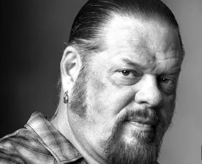 Black and white portrait of a man with a goatee and earrings.