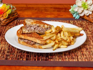 Patty melt sandwich with fries on a white plate.