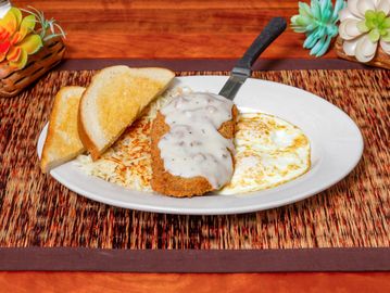 Country fried steak with gravy, eggs, toast, and hashbrowns.