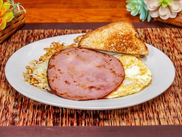 Breakfast plate with ham, eggs, toast, and hash browns.