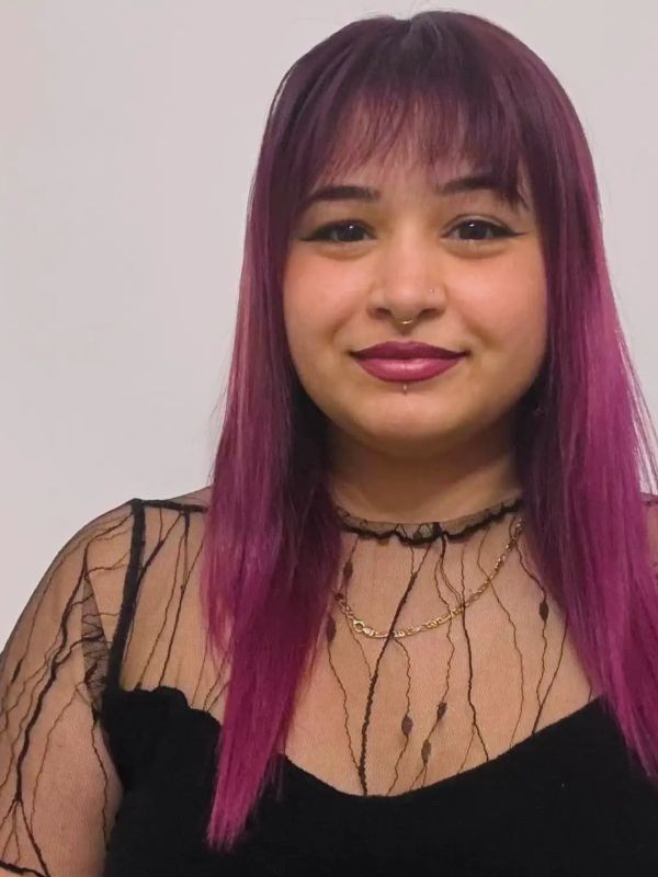 Young woman with purple hair and a black lace top.