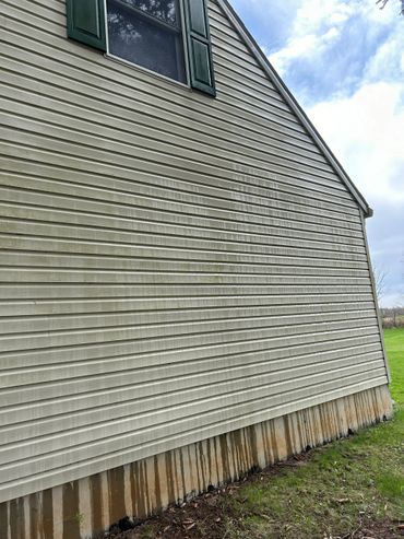 Dirty exterior wall of a house with streaks of dirt and stains.