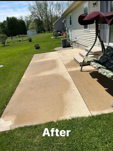 Cleaned concrete patio with fresh, wet patches and a garden swing on the side.