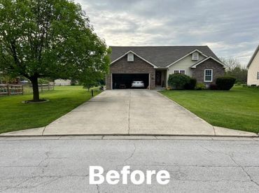 Front view of a house with a plain concrete driveway and green lawn.