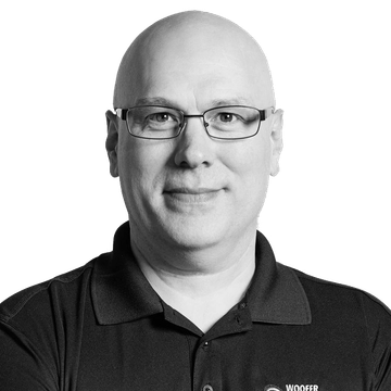 Smiling bald man in glasses and black polo shirt.