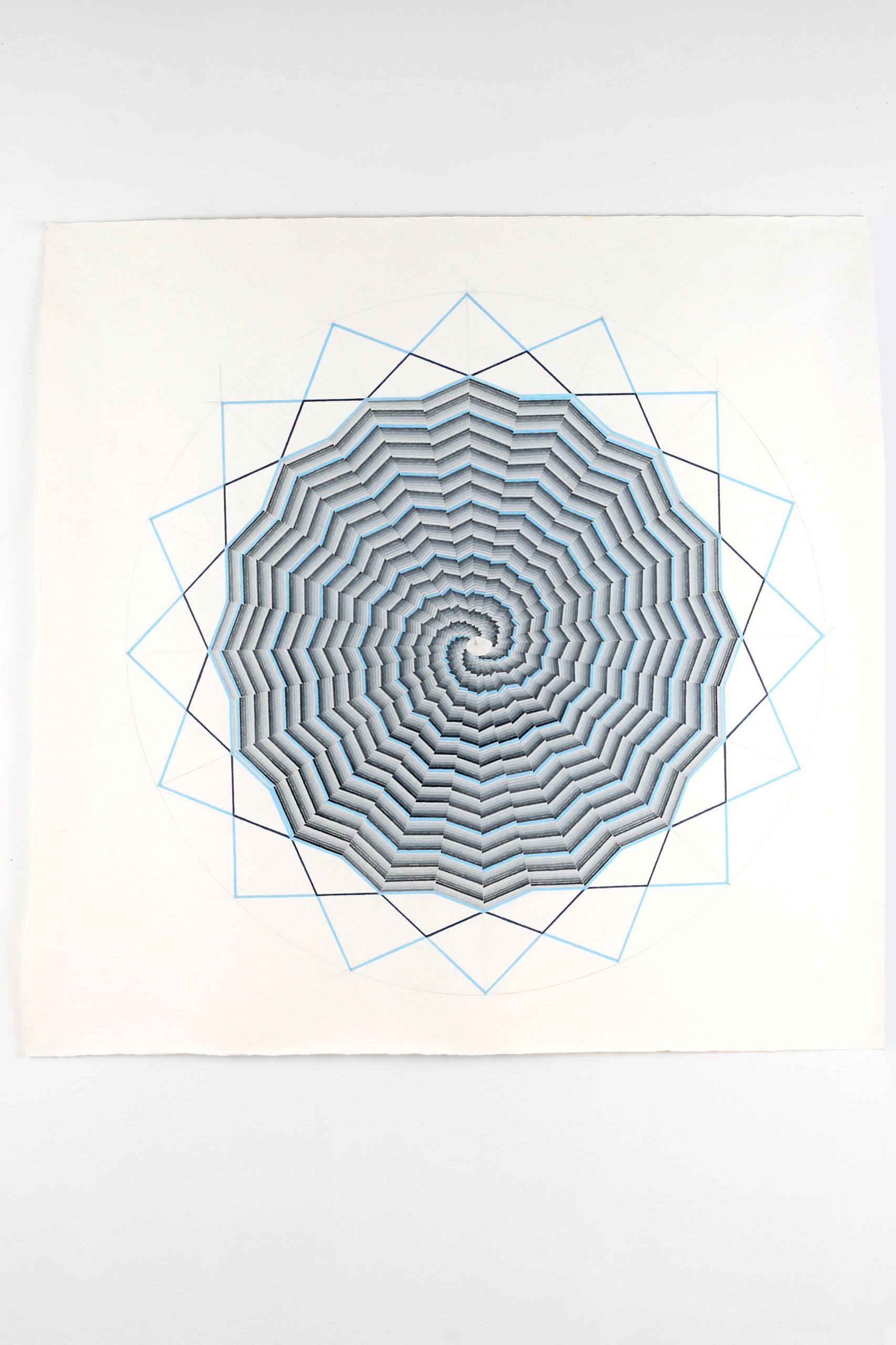 Geometric spiral pattern on paper with blue and black lines.