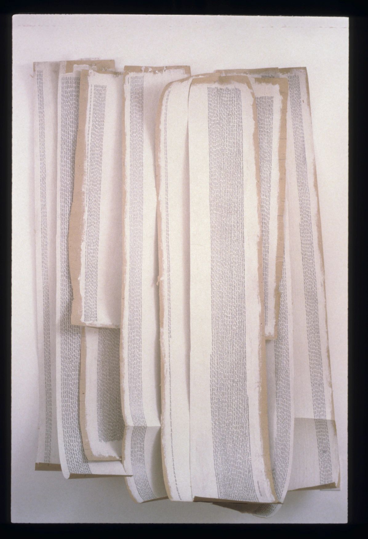 Art installation with long strips of paper covered in tiny text.