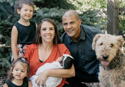 A happy family with two children and a dog outdoors.
