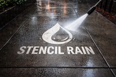 A pressure washer cleaning a wet sidewalk with a stencil rain logo.