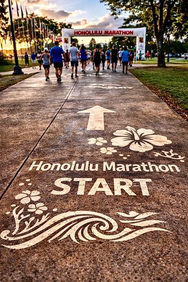 Participants gather at the Honolulu Marathon starting line during sunrise.