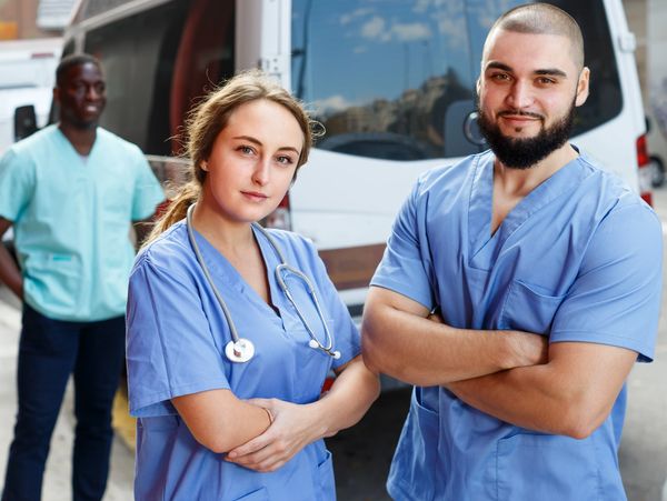 Three medical professionals standing outside, two in focus.