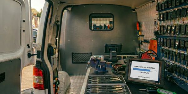 Inside a work van with tools and a laptop updating software.