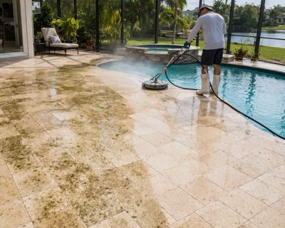 Professional pressure washing technician surface cleaning a residential pool patio in Palm Bay, FL