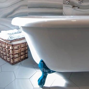 A bathroom with a clawfoot tub and basket of towels.