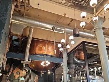 Industrial-style interior with exposed pipes, metal tanks, and vintage chandeliers.