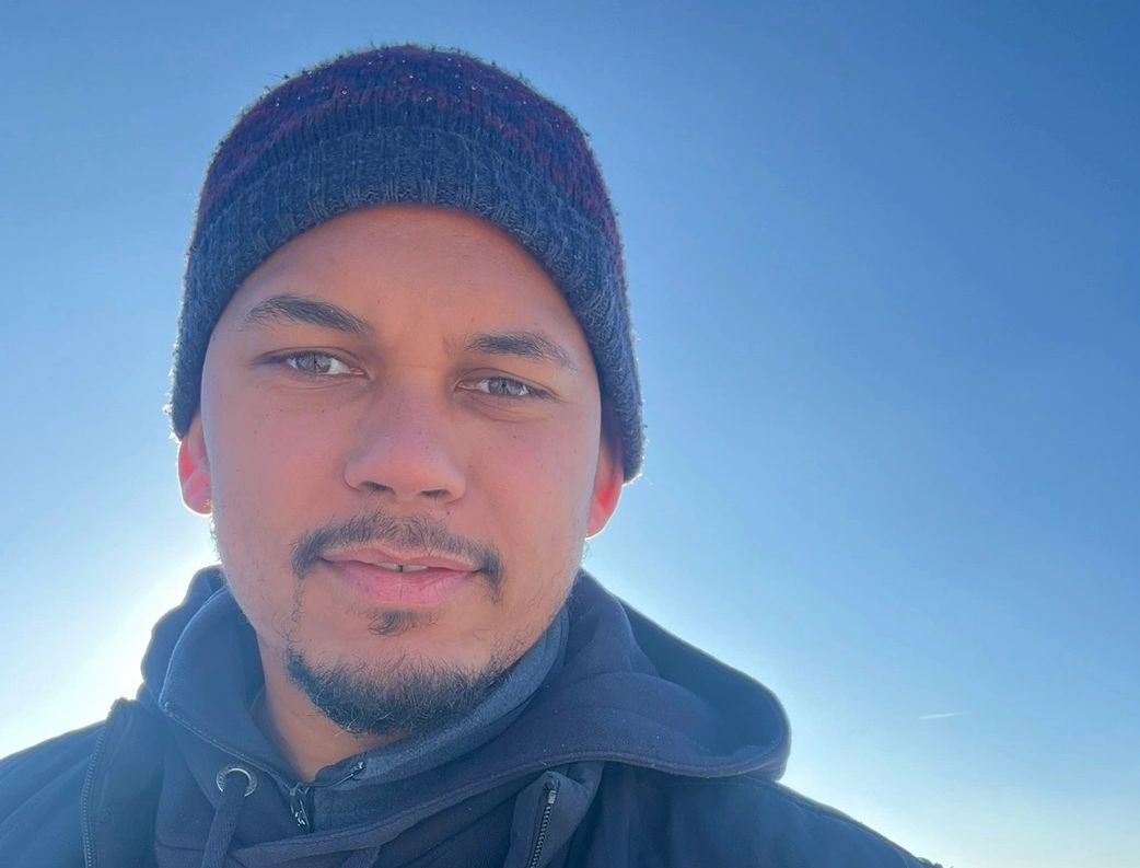 man outside with a hat and hoody. blue skies on a sunny day