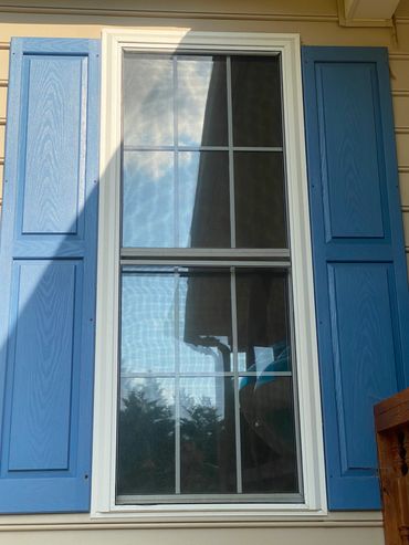 Home window tint on single-pane window with blue shutters.