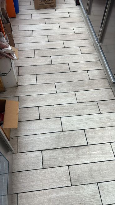 Light gray rectangular tiles arranged in a staggered pattern on a floor.
